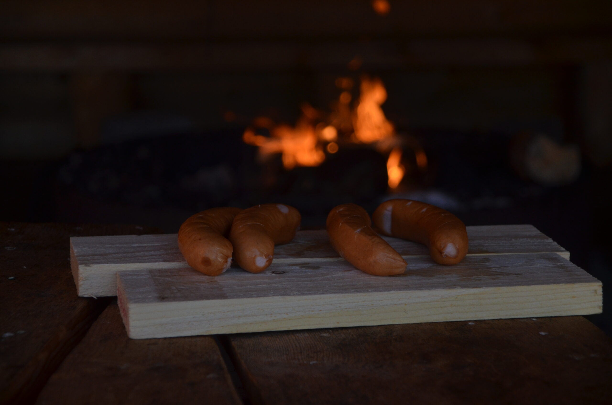 makkaroita puisen tarjottimen päällä, taustalla näkyy nuotio